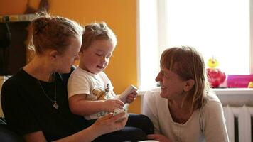 Two year-old boy plays with his mother and grandmother video