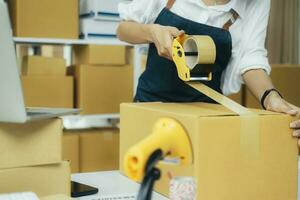 Online entrepreneur using scotch tape to seal parcel box. photo