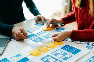 UX developer and ui designer brainstorming about mobile app interface wireframe design with customer breif and color code at office. photo
