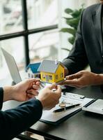 agente de bienes raíces que presenta y consulta al cliente para la toma de decisiones firmar un acuerdo de formulario de seguro, modelo de hogar, en relación con la oferta de préstamo hipotecario foto