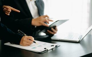 Business documents on office table with smart phone and calculator digital tablet and graph business with social network diagram and two colleagues discussing data working in the office photo
