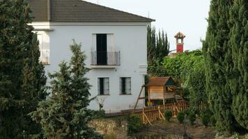 Exterior of two-storey house with kids space and big pine trees aside video