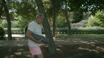 homme dans le parc avec une yoga tapis video