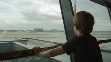 Young traveller likes watching departing planes at the airport video