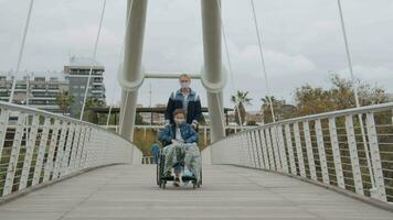 madre caminando con hijo en silla de ruedas video