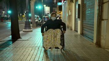 fauteuil roulant balade dans le soir ville. désactivée enfant en plein air video