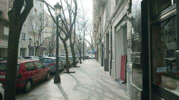 vacío calle con estacionado carros y escaparates en soleado mañana, Valencia video