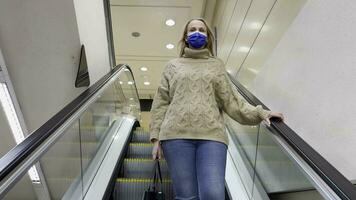 Woman in medical mask getting downstairs by escalator in trade centre video