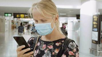 sie Überprüfung Mitteilungen Vor das Flug. Frau im Maske mit Zelle beim das Flughafen video