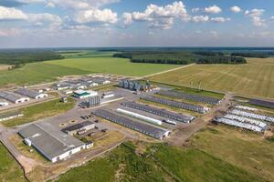 aerial panoramic view over livestock farm and agro-industrial complex with silos and rows of barns, pigsties, chicken coops photo