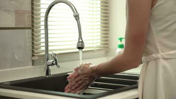 Woman hands rinse plate at the kitchen sink doing the chores at home. Dish washing routine. photo