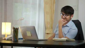 contento asiático hombre trabajando en línea con ordenador portátil a hogar oficina, teletrabajo concepto. foto