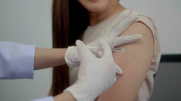 Close up hand asian woman doctor injecting in arm of asian girl. photo