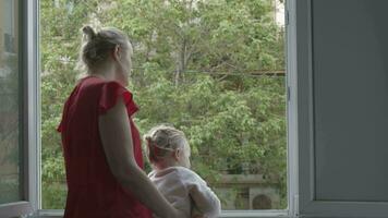 mãe com filha levando a ar dentro aberto janela durante coronavírus isolamento video