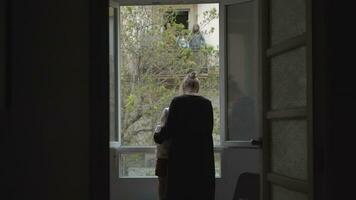 Mum with little daughter by open window during coronavirus lockdown video