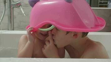 Kids bathing and having fun. They want to be unnoticed under toy bathtub video