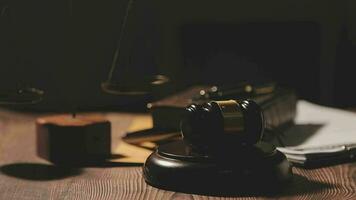 concetto di giustizia e diritto. giudice maschio in un'aula di tribunale con il martelletto, lavorando con computer e tastiera docking, occhiali, sul tavolo alla luce del mattino video