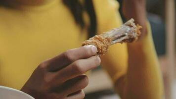 detailopname beeld van een mooi Aziatisch vrouw genieten aan het eten Frans Patat en gebakken kip in restaurant video