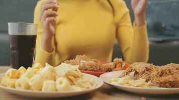fechar-se imagem do uma lindo ásia mulher apreciar comendo francês fritas e frito frango dentro restaurante video