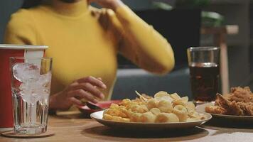 detailopname beeld van een mooi Aziatisch vrouw genieten aan het eten Frans Patat en gebakken kip in restaurant video