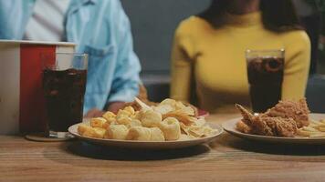 avvicinamento Immagine di un' bellissimo asiatico donna godere mangiare francese patatine fritte e fritte pollo nel ristorante video