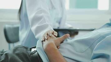 Professional female doctor smiles and shows positive examination results to young, joyful man. Handsome, happy guy with glasses at doctor's appointment in modern office of medical institution. video