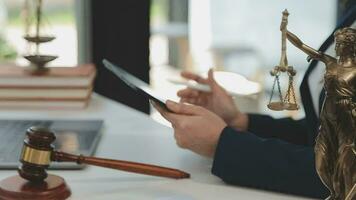 concetto di giustizia e diritto. giudice maschio in un'aula di tribunale con il martelletto, lavorando con computer e tastiera docking, occhiali, sul tavolo alla luce del mattino video