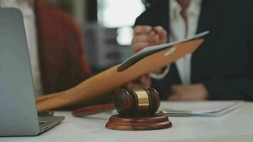 concetto di giustizia e diritto. giudice maschio in un'aula di tribunale con il martelletto, lavorando con computer e tastiera docking, occhiali, sul tavolo alla luce del mattino video