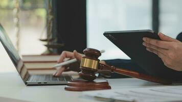 Justice and law concept.Male judge in a courtroom with the gavel, working with, computer and docking keyboard, eyeglasses, on table in morning light video