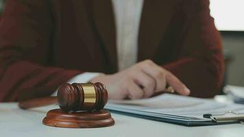 concetto di giustizia e diritto. giudice maschio in un'aula di tribunale con il martelletto, lavorando con computer e tastiera docking, occhiali, sul tavolo alla luce del mattino video