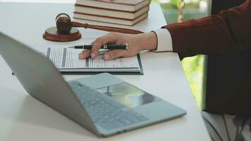 concetto di giustizia e diritto. giudice maschio in un'aula di tribunale con il martelletto, lavorando con computer e tastiera docking, occhiali, sul tavolo alla luce del mattino video