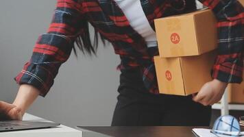 Emprendedora de pequeñas empresas o mujer asiática independiente que usa una computadora portátil con caja, joven mujer asiática de éxito con su mano levantada, caja de embalaje de marketing en línea y entrega, concepto de pyme. video