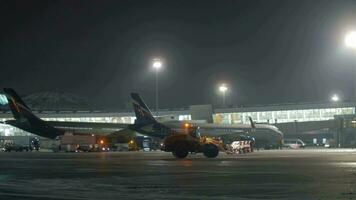 terminal d do sheremetyevo aeroporto com aviões e neve arado trator. noite Visão video