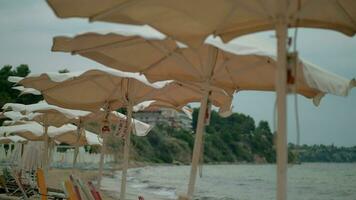 Windy weather on the sea shore Empty beach and shaking sun umbrellas, Greece video