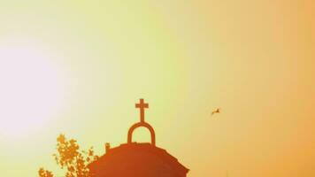 iglesia y pájaro volador contra el brillo de la puesta de sol brillante video