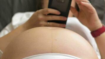 embarazada mujer con celúla, bebé pateando el barriga video