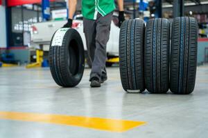 Auto Mechanic with New tires that change tires in the auto repair service center, blurred background, the background is a new car in the stock blur for the industry, a four-wheeled tire set. photo