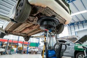 automotor industria, coche reparar estación pavimentado con epoxy piso y eléctrico levantar para un coche ese viene a cambio el motor petróleo en el antecedentes de coche reparar centrar con epoxy pisos foto