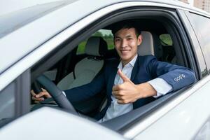 A businessman thumbs up while sitting in a new electric car with a happy smile. EV Car. EV vehicle. Concept of green energy and reduce CO2 emission. photo