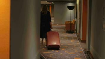 Woman with suitcase walking to the room in hotel corridor video