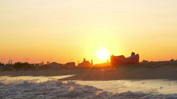 puesta de sol escena de hombre relajante en inflable cama solar a el playa video