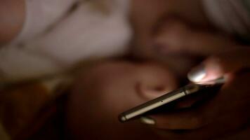 mère surfant l'Internet sur cellule lorsque allaitement maternel bébé video