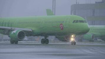 Plane of S7 Airlines driving on runway at Domodedovo Airport, view in snowfall video