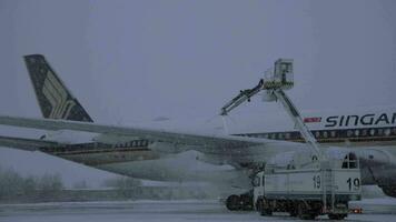 Spraying de-icing fluid on the plane of Singapore Airlines in snowy evening video