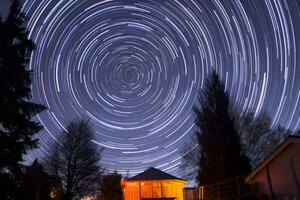 star trails over a small cabin in the night sky generative AI photo