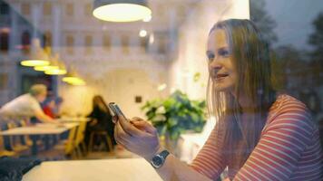 Happy woman in cafe thinking over sms she typing video
