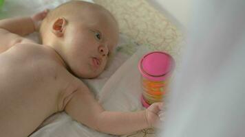 bebé niña de dos mes acostado en cuna con traqueteo caja video