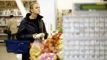 jovem mulher compras dentro supermercado e escolhendo legumes video