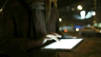 vrouw wandelen in de avond straat en gebruik makend van tablet computer video