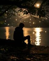 a person sitting under a tree at night by the water generative ai photo